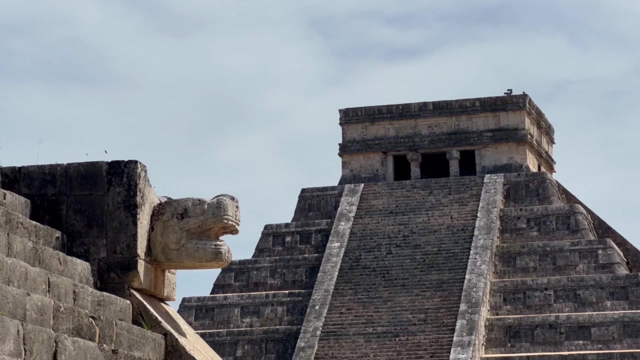 Ripresa ravvicinata a mano libera con panning di intagli in pietra di giaguaro verso la Piramide di Kukulkan a Chichen Itza, Messico. 4K.