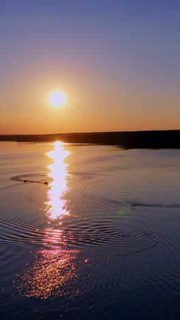 beautiful sunset in nature. sunny path reflects on the river in the evening. amazing view on the lake against the setting sun. vertical video