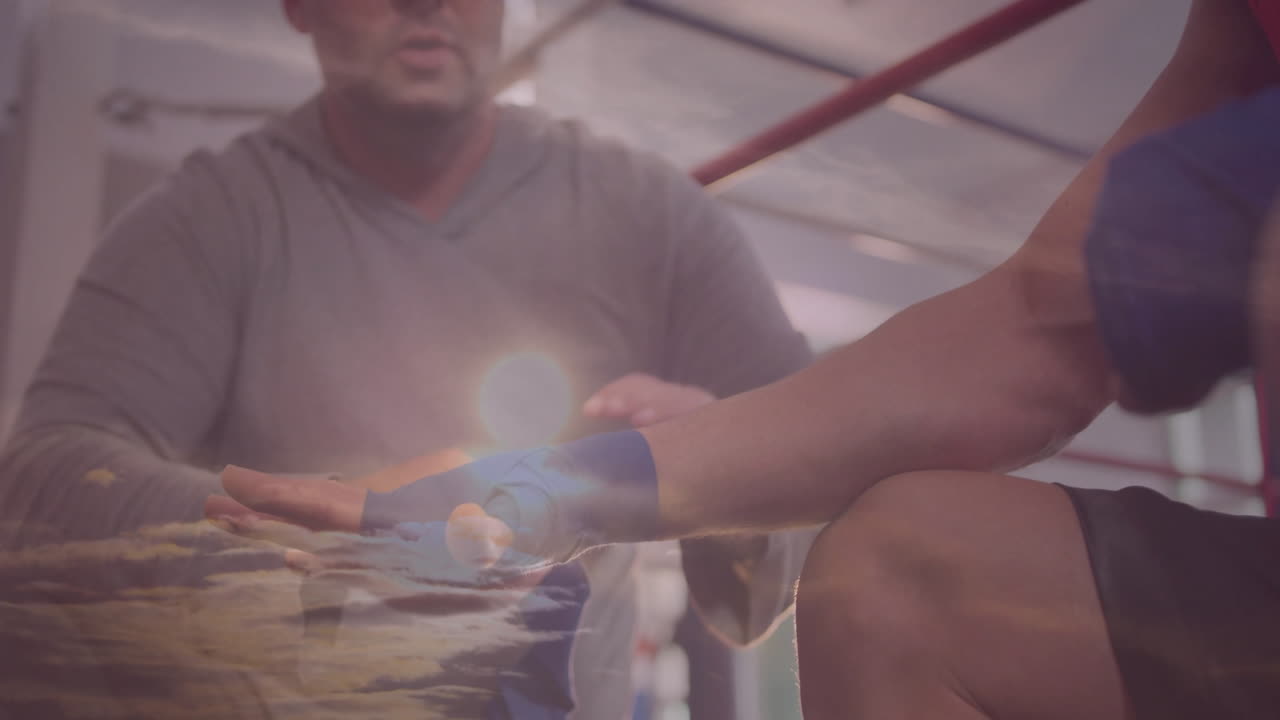 In gym, boxer with hand wrapped under sunset sky animation overlay