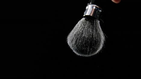 person hand splashing water from shaving brush against black background 4k