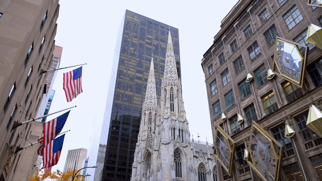 New York, USA, 22 October 2025: The facade of Saks Fifth Avenue and tops of the St. Patrick's Cathedral. American flags hang on the façade of the opposite building. New York, USA