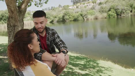 feliz pareja afroamericana sentada en un banco en el lago en el bosque, cámara lenta