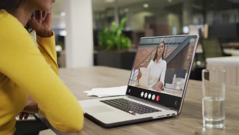 Mujer-Birracial-Usando-Una-Computadora-Portátil-Para-Videollamada,-Con-Un-Colega-De-Negocios-En-La-Pantalla