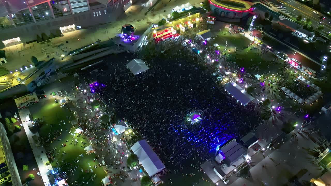 Flashing lights and celebrating crowd of people during open wir festival in American town. Aerial top down shot. Musical festival with band on stage in Atlanta, Georgia.Night scene with blinking light