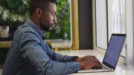 african american businessman using laptop in modern cafe