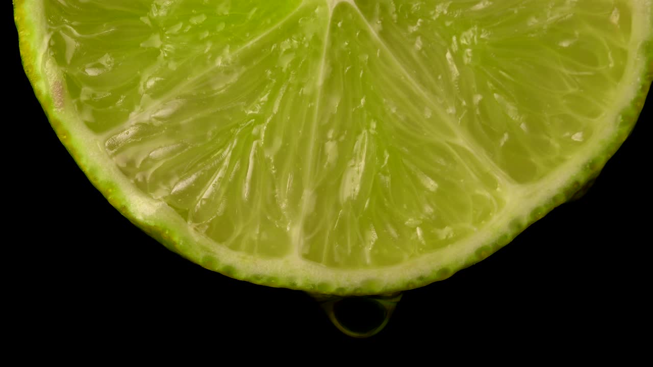 una jugosa rebanada de lima verde con una gota de jugo.