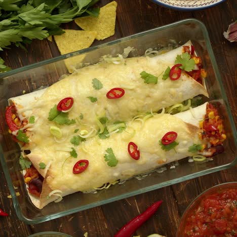 homemade vegetable burritos served in heatproof dish  with salsa  guacamole  nachos and ingredients