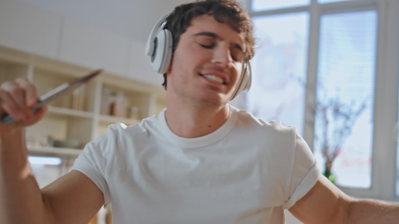hombre alegre cantando cocinando desayuno en auriculares en casa de cerca. chico bailando