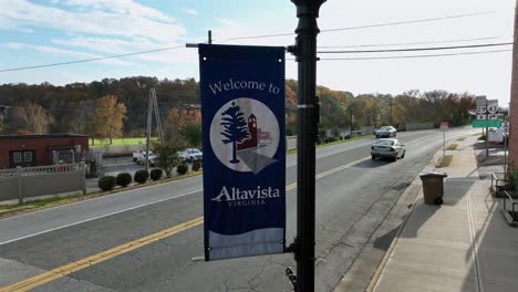 welcome to altavista, virginia flag on streetlamp of city. driving cars on street in historic town during autumn day. aerial close up shot.