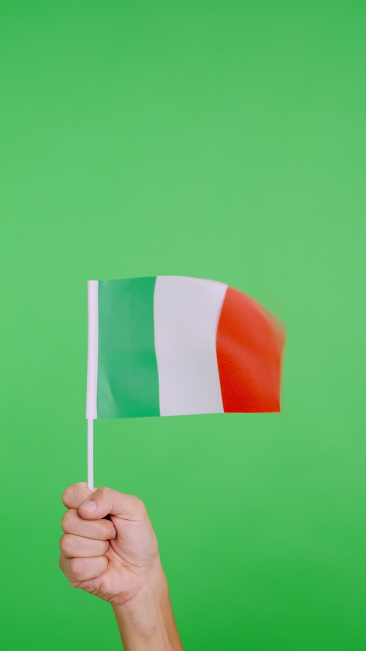Mano che solleva un gagliardetto italiano mentre sventola al vento