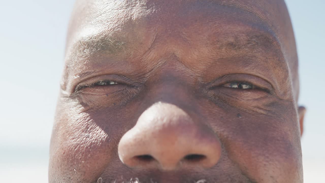 retrato de un feliz anciano afroamericano sonriendo en la playa, en cámara lenta
