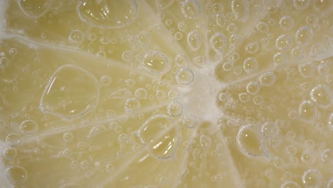 ripe lime slice under water with air bubbles. macro background.