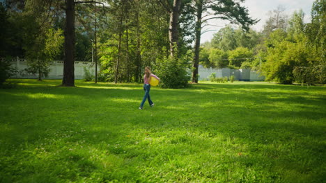 back view of young girl walking happily with yellow balloon under arm in sunny green park, long hair swaying as she walks across vibrant grass, sunlight casting soft tree shadows on bright field
