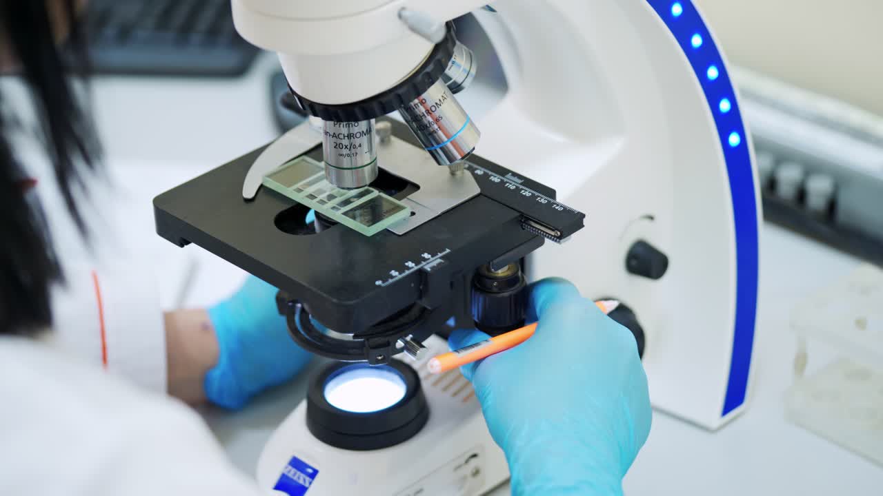 Laboratory examination of blood. Close up of female scientist in uniform working with microscope in the laboratory