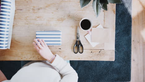 Overhead-Shot-Looking-Down-On-Woman-At-Home-Gift-Wrapping-Present