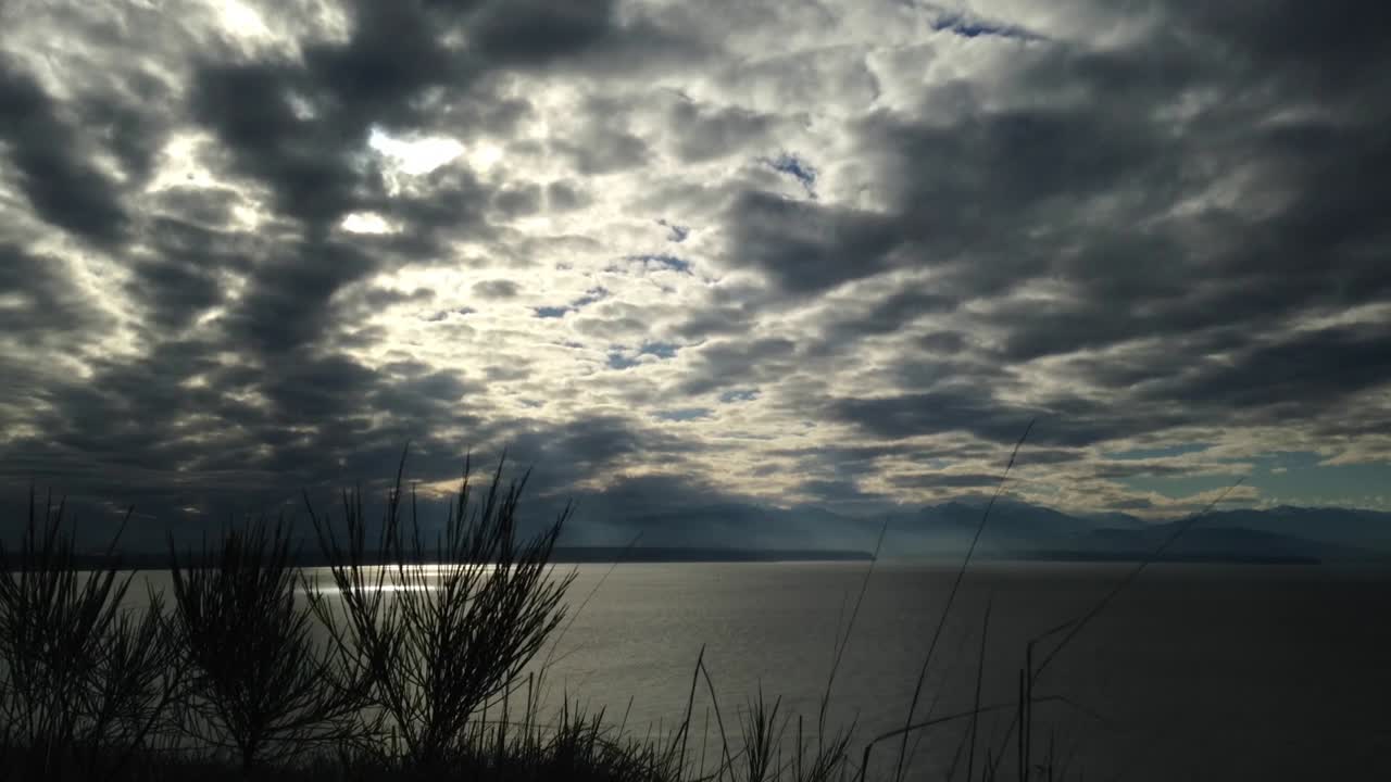 Time lapse of sun rays shining down through through and amazing sky over the Olympic Mountains and Puget Sound