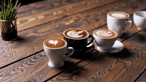 assortment of coffee cups with latte art on a wooden table