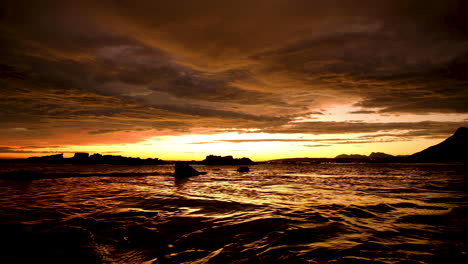 Puesta-De-Sol-De-Fuego-Sobre-El-Océano,-Paisaje-De-Nubes-Iluminado-En-Naranja,-Superficie-De-Mar-De-Oro-Líquido