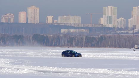 blue car test drive on frozen lake in front of city