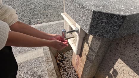 person washing hands under running water outdoors