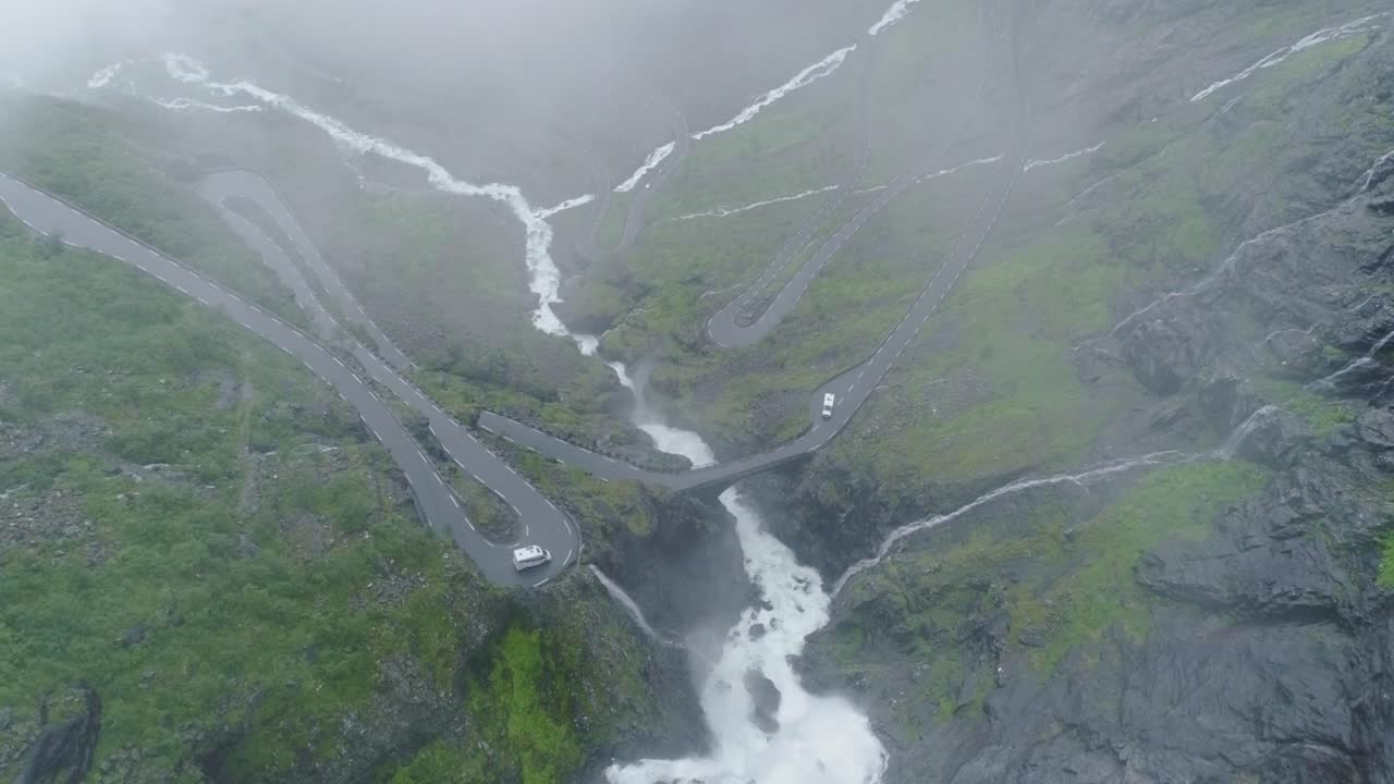 imágenes de drones de trollstigens brumosos con coches, un puente y dramáticas cascadas