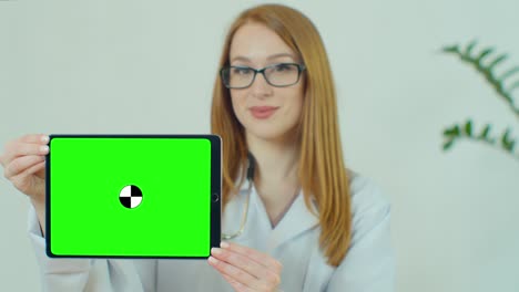 doctora con gafas que demuestra una tableta digital con llave de croma en el hospital, retrato de una mujer con túnica blanca con estetoscopio en el consultorio médico que muestra una tableta virtual con pantalla verde.