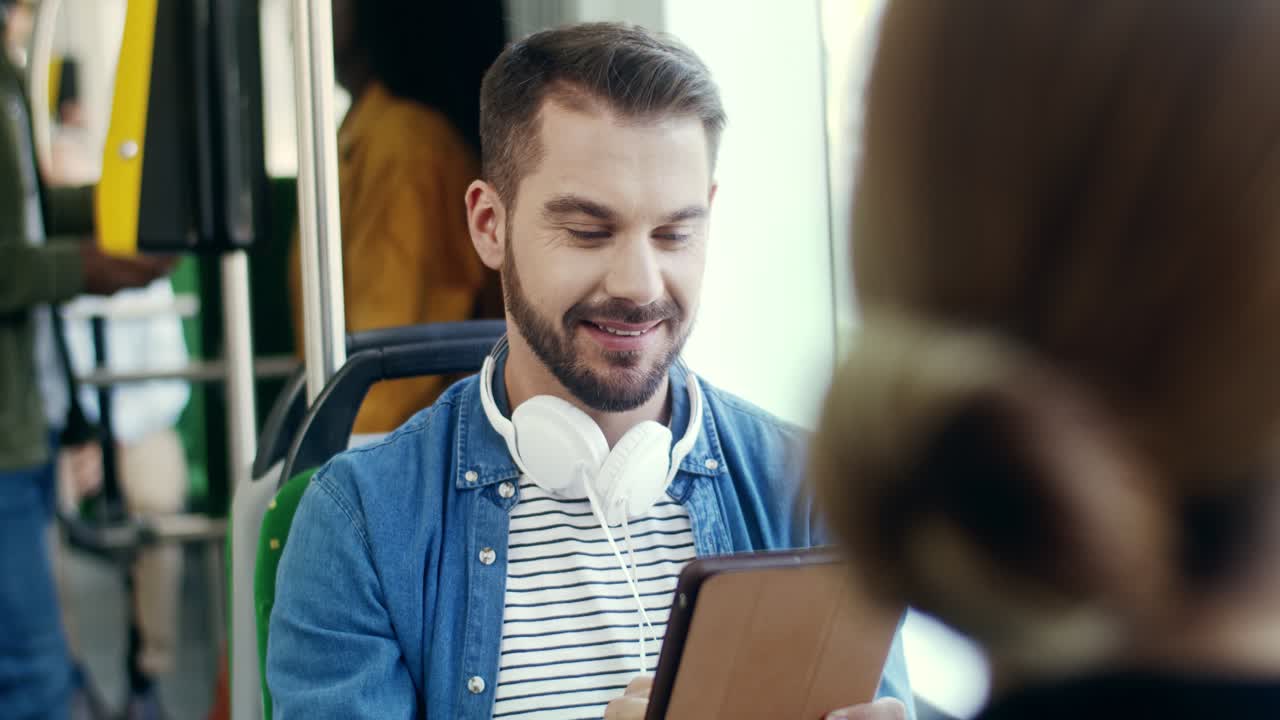 barista sonriente en delantal dando café al cliente en una taza de papel y agradeciéndole el pedido en el mostrador de la cafetería
