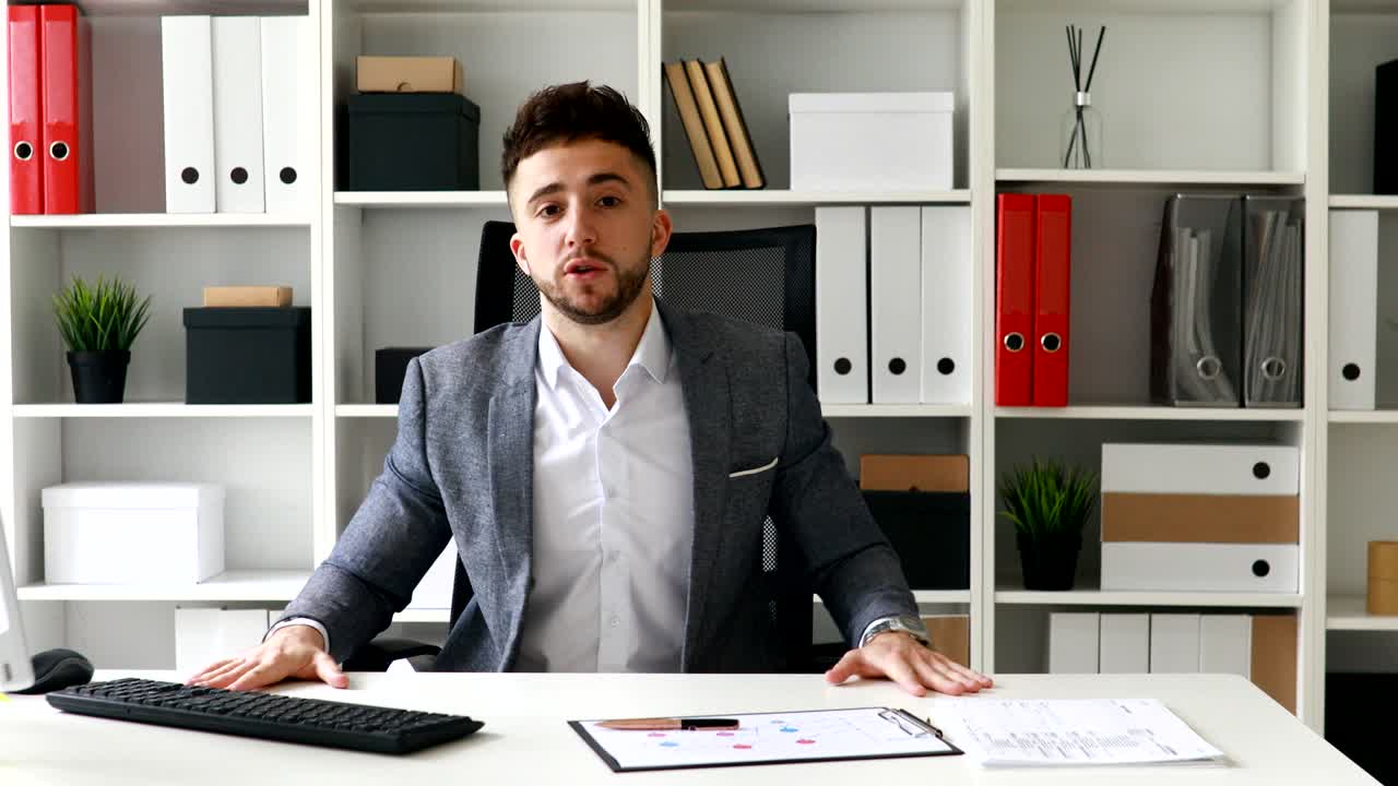 giovane uomo d'affari adulto sul posto di lavoro che guarda la telecamera in un ufficio moderno