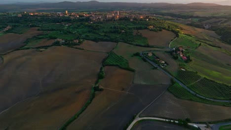 aerial at sunset over the tuscany landscape with the city of pienza at the top of the hill, province of siena, italy