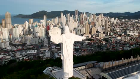 panel de vista aérea a la izquierda de cristo el remeeder en balneario camboriu, brasil con la ciudad, la playa y las montañas en el fondo