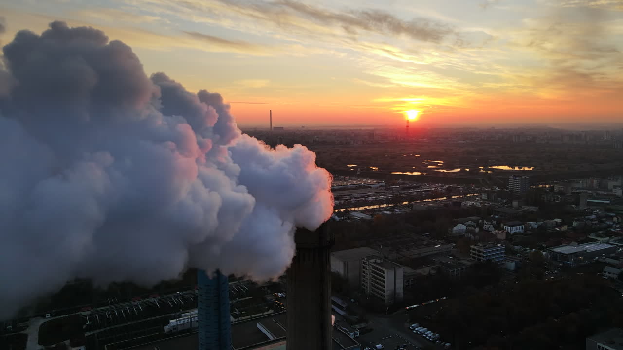 Power station with a lot of tubes and facilities in Bucharest at sunset, a lot of foam from inside a tube. Cityscape, view from the drone flying through the foam, Romania