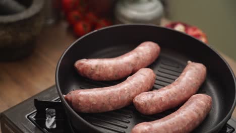 crop person turning homemade sausages frying in pan