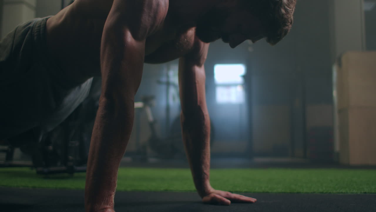 un hombre fuerte realiza flexiones desde el suelo con toda su fuerza. un hombre inflado hace flexiones en el gimnasio