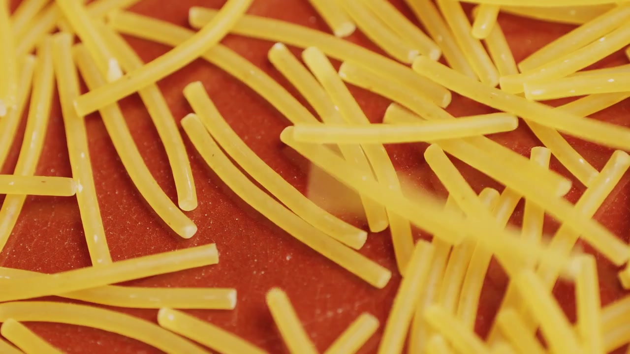 Pastina che cade su una superficie rossa al rallentatore