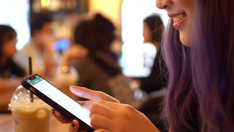 engaging moment: a young woman smiles while using her smartphone in a cozy café setting, showcasing modern technology and social interaction