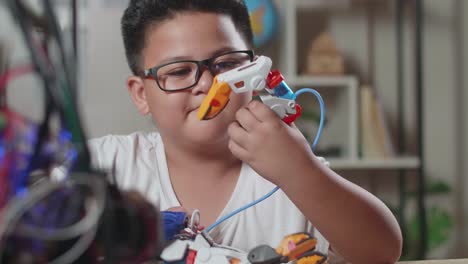 primer plano de un chico asiático bonito comprobando una mano de cyborg en casa