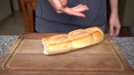 Guy-Put-And-Show-Cuban-Bread-On-Wooden-Chopping-Board