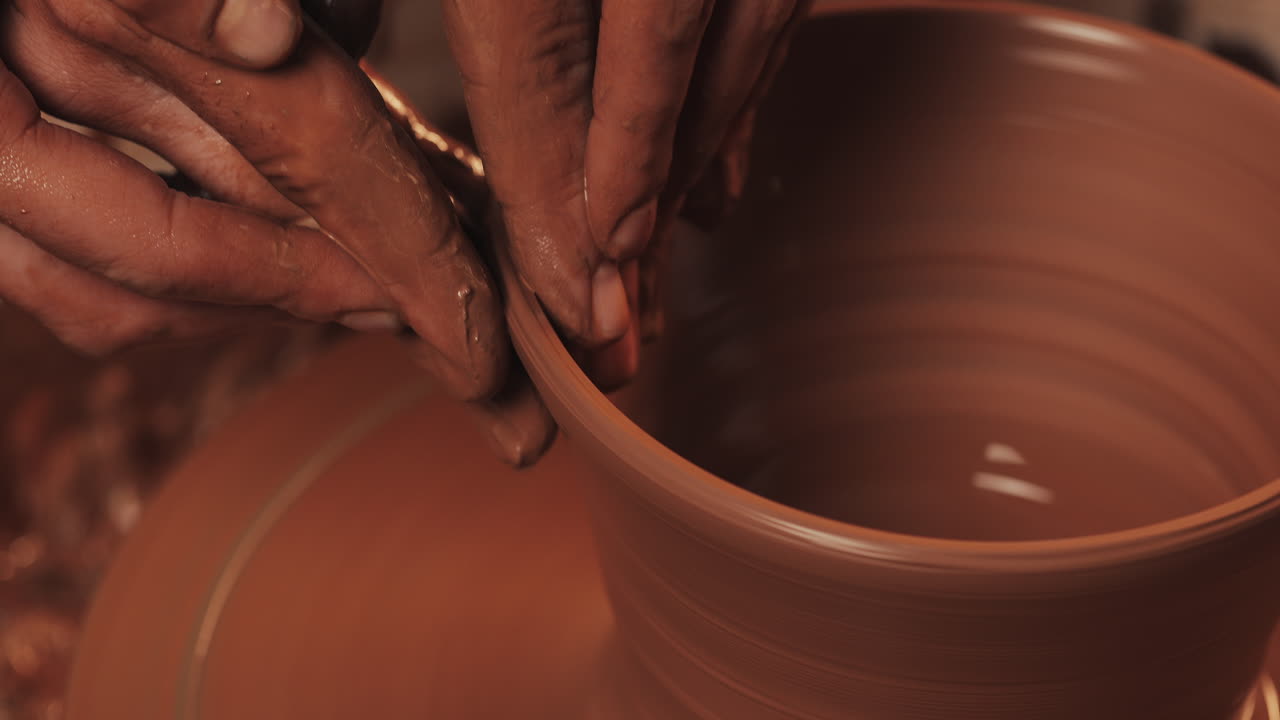 manos moldeando arcilla en una rueda de cerámica