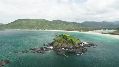 Small-Bolog-Island-sticking-out-of-the-water-near-Nacpan-Beach,-El-Nido,-Palawan,-Philippines