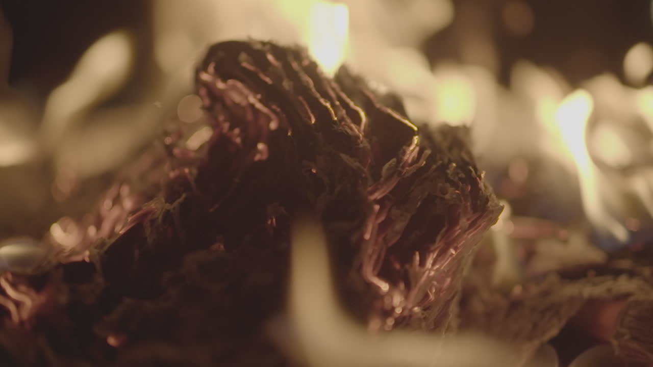 Slowmotion shot of a fire and flames burning away a newspaper in a fire pit creating sparks and smoke LOG