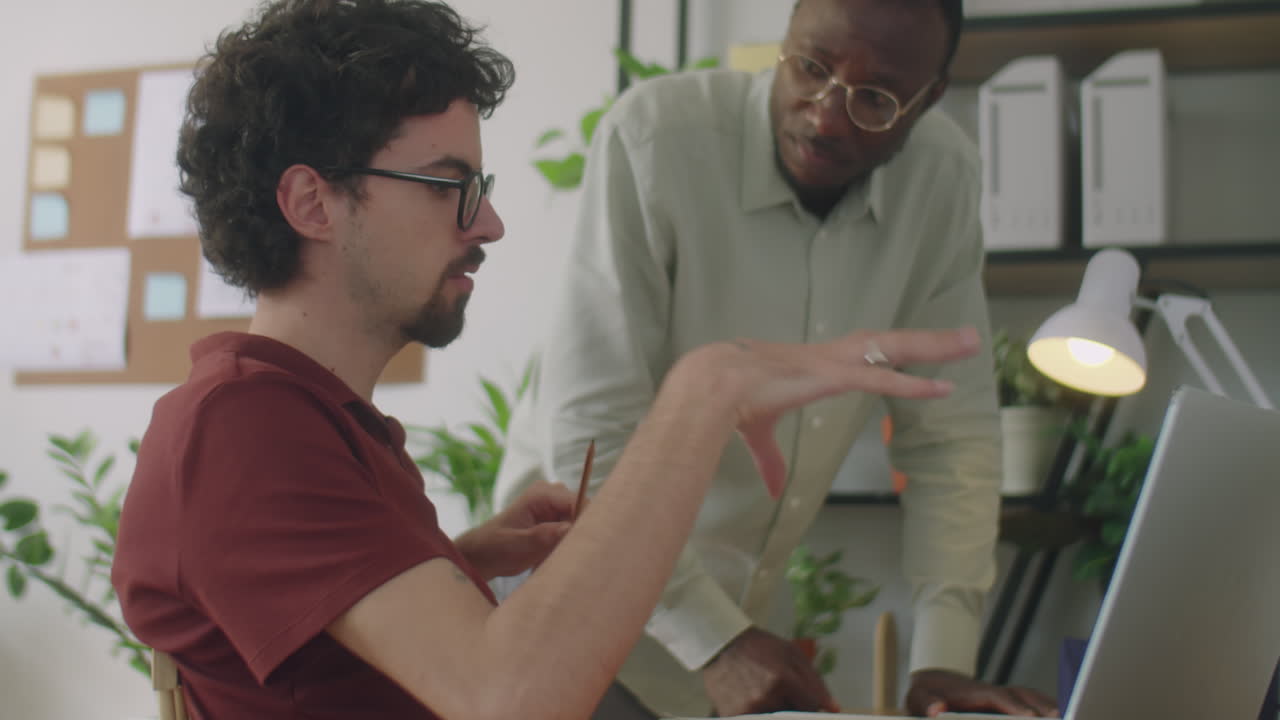 Diverse Office Workers Discussing Business Project on Laptop
