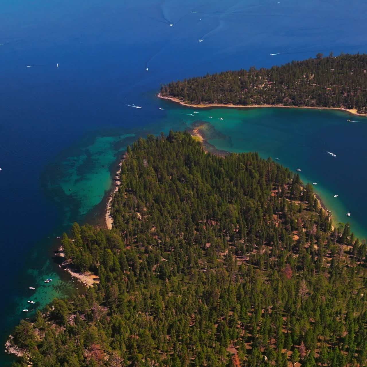 Beautiful blue water of Lake Tahoe, California, USA. Speed boats sailing by the water. Wooded banks from aerial perspective