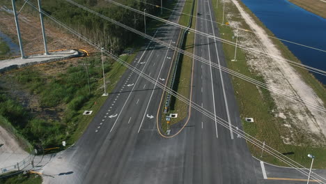 Slow-aerial-reveal-of-open-road-and-sky-through-powerlines