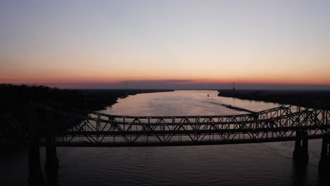 wide panning aerial shot of the natchez-vidalia bridge on the mississippi river at sunset