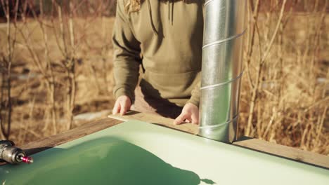 a man is placing a small plank into the corner of the diy hot tub basin - close up