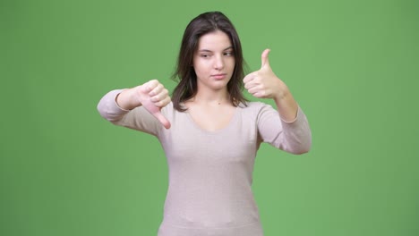 young beautiful woman choosing between thumbs up and thumbs down