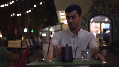 man enjoying a drink at a cafe at night