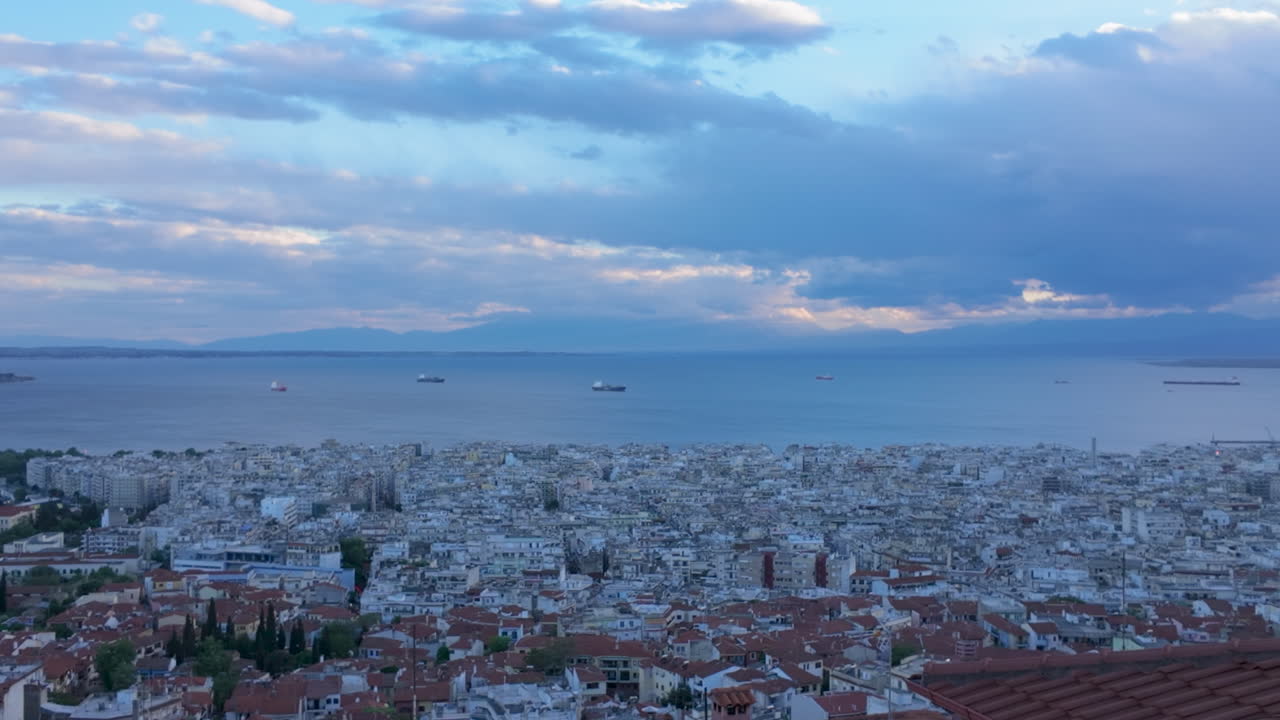 Vista aerea di una città costiera greca con navi sul mare calmo e nuvole spettacolari sopra durante il giorno
