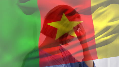 digital composition of cameroon flag waving against stressed caucasian woman at hospital
