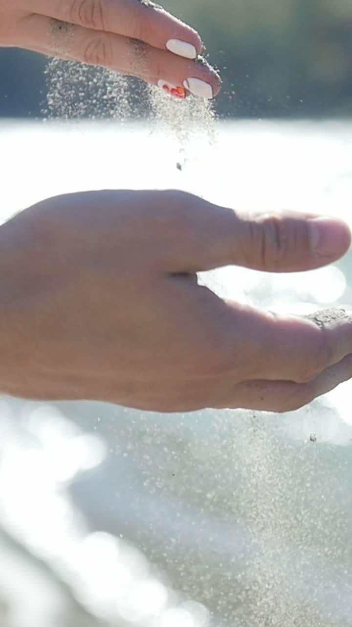 Hand pouring sand into water